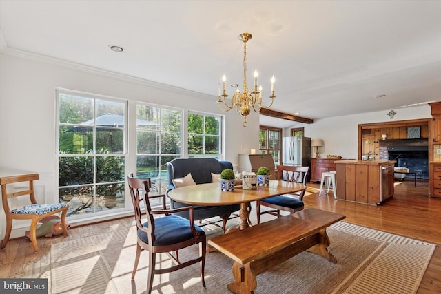 dining space with ornamental molding, light wood finished floors, and a notable chandelier
