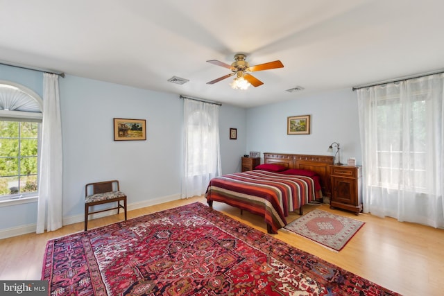 bedroom featuring a ceiling fan, baseboards, visible vents, and wood finished floors