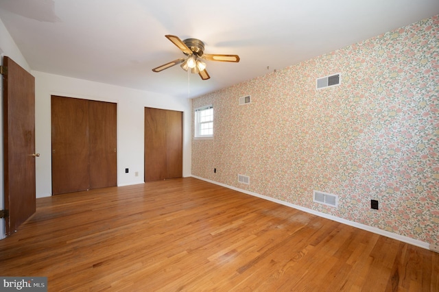 11 Whitekirk Dr, Wilmington, DE 19808 - unfurnished bedroom featuring light wood-style floors, multiple closets, wallpapered walls, and visible vents