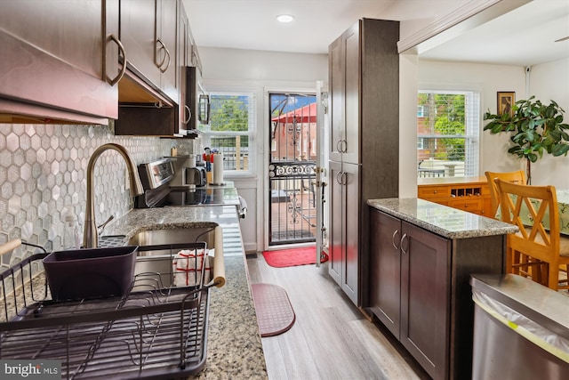 4311 Chatham Rd, Baltimore, MD 21207 - kitchen with light wood-style flooring, dark brown cabinets, tasteful backsplash, light stone counters, and stainless steel microwave