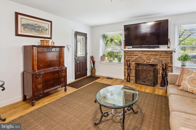 4311 Chatham Rd, Baltimore, MD 21207 - living room featuring a stone fireplace, wood finished floors, and baseboards