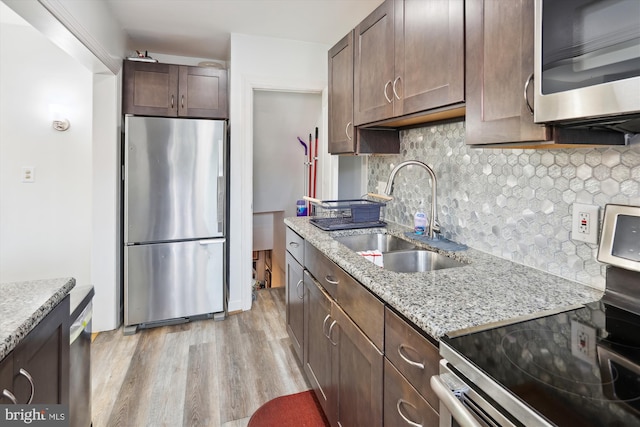 4311 Chatham Rd, Baltimore, MD 21207 - kitchen with appliances with stainless steel finishes, a sink, light wood finished floors, dark brown cabinets, and tasteful backsplash