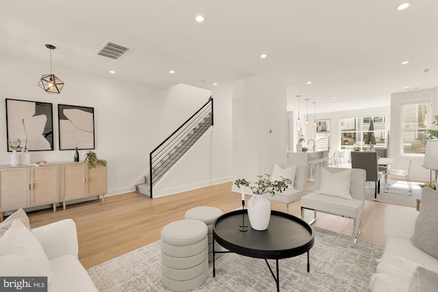 living room with visible vents, stairway, baseboards, light wood finished floors, and recessed lighting