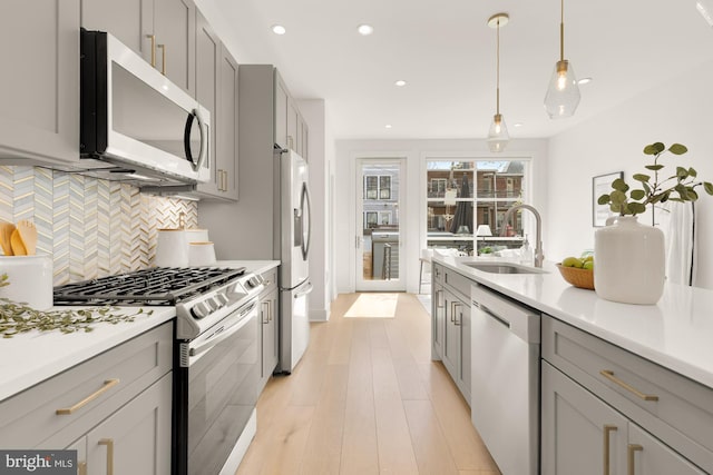 kitchen with a sink, decorative backsplash, gray cabinets, and stainless steel appliances