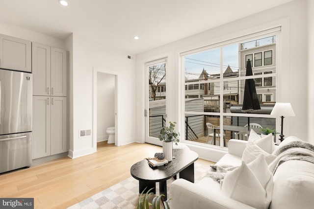 living room with recessed lighting, baseboards, light wood finished floors, and visible vents