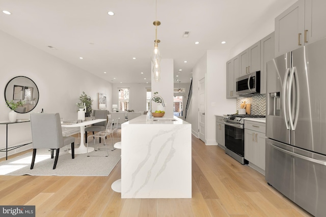kitchen featuring recessed lighting, tasteful backsplash, a sink, light wood-style flooring, and appliances with stainless steel finishes