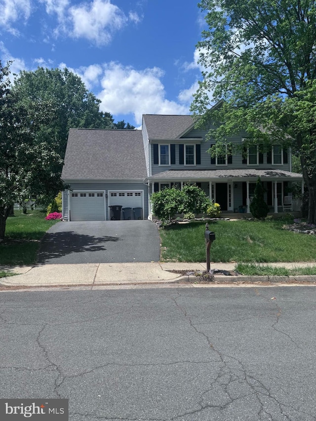 colonial home with roof with shingles, an attached garage, a front lawn, covered porch, and driveway