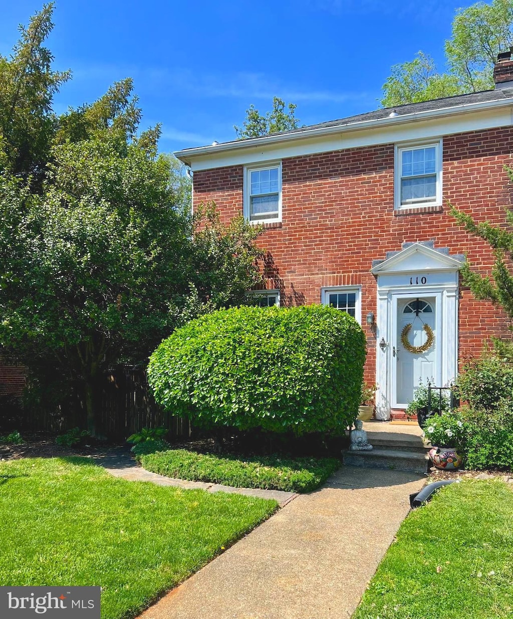 view of front of home with brick siding, a front yard, and a chimney