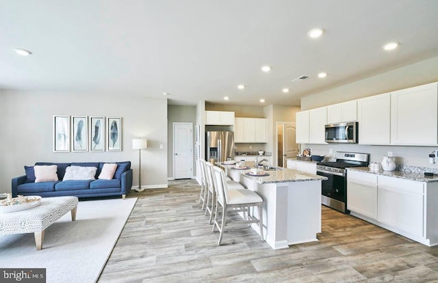 kitchen with appliances with stainless steel finishes, white cabinets, light wood-type flooring, and recessed lighting