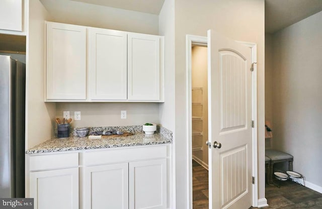 interior space featuring dark wood-type flooring, freestanding refrigerator, and baseboards
