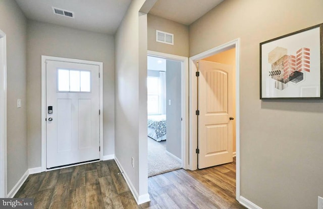 entryway with baseboards, visible vents, and wood finished floors