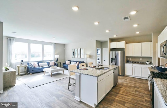 kitchen featuring visible vents, open floor plan, a sink, dark wood finished floors, and appliances with stainless steel finishes