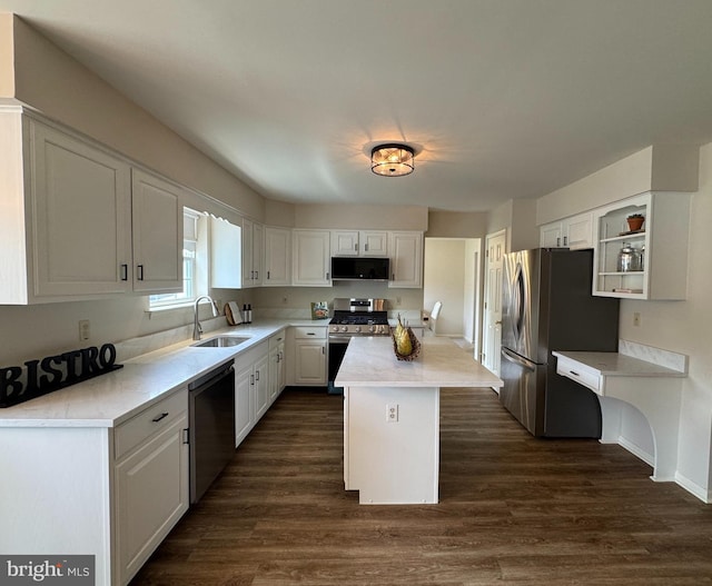 kitchen with a kitchen island, a sink, white cabinetry, dark wood-type flooring, and appliances with stainless steel finishes