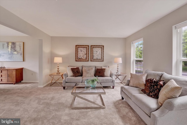 living area with plenty of natural light, light colored carpet, and baseboards