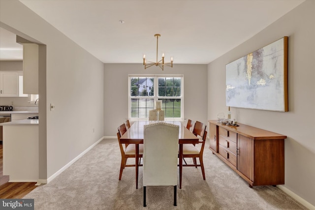dining space featuring light carpet, a chandelier, and baseboards
