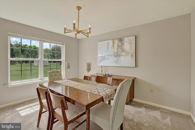 dining room with a chandelier, baseboards, and light colored carpet