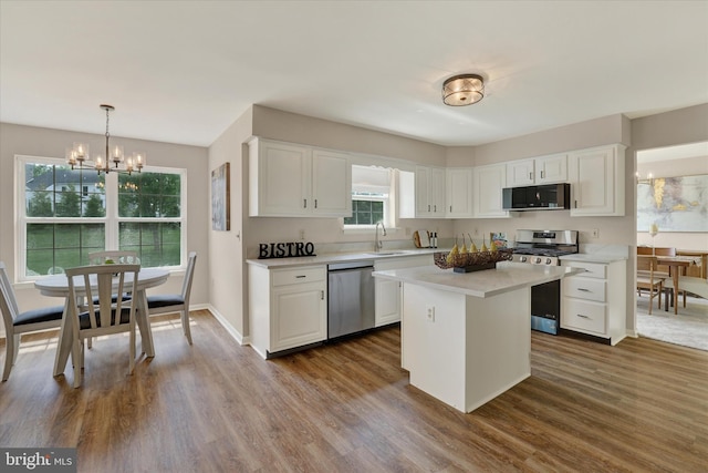 kitchen with appliances with stainless steel finishes, a chandelier, a sink, white cabinetry, and light countertops