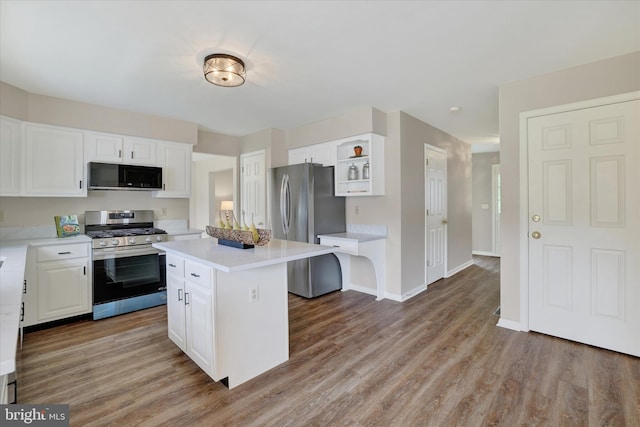 kitchen with appliances with stainless steel finishes, white cabinetry, light countertops, light wood-type flooring, and a center island