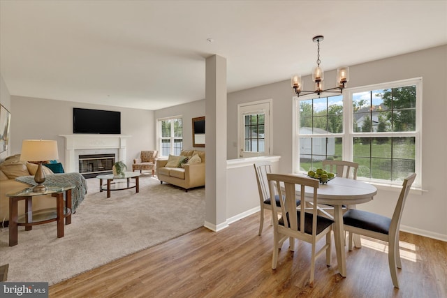 dining room featuring wood finished floors, a chandelier, baseboards, and a premium fireplace