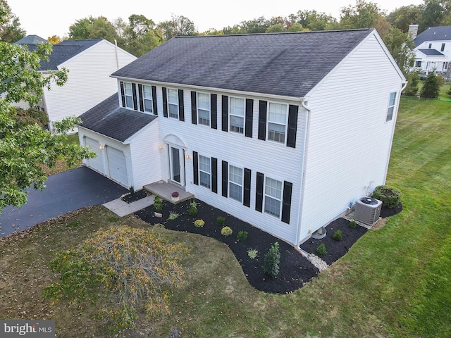 view of front facade featuring central air condition unit, a garage, a shingled roof, and aphalt driveway
