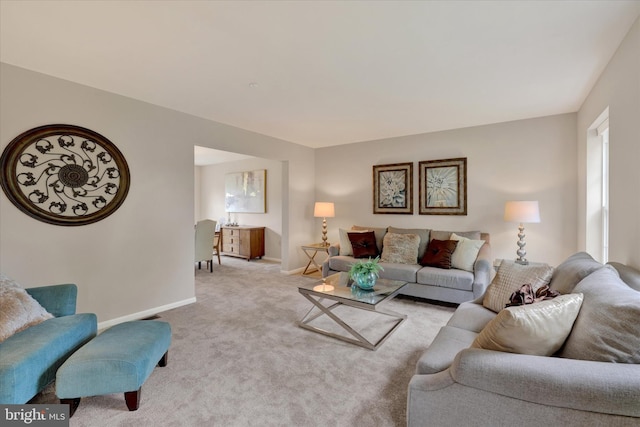 living area featuring baseboards and light carpet