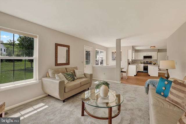 living area featuring healthy amount of natural light, light colored carpet, and baseboards