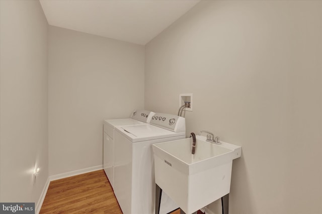 laundry area with washing machine and dryer, light wood finished floors, and baseboards