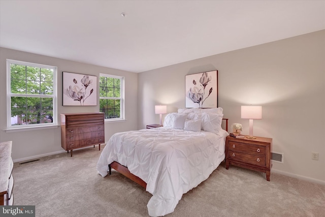bedroom with light colored carpet and baseboards