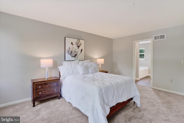 bedroom with light colored carpet, baseboards, and connected bathroom