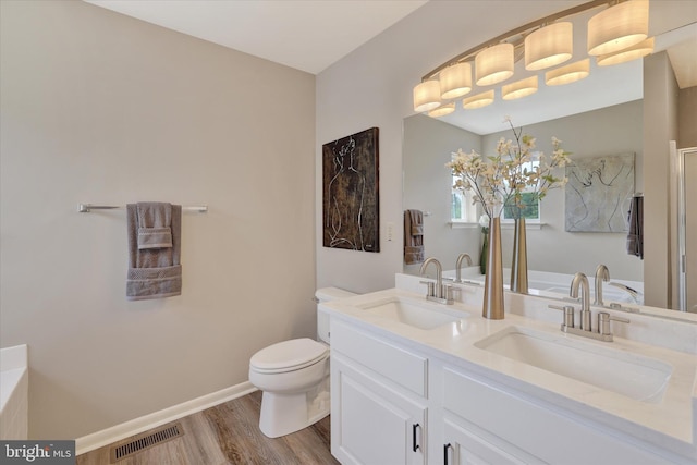bathroom featuring wood finished floors, toilet, double vanity, and baseboards