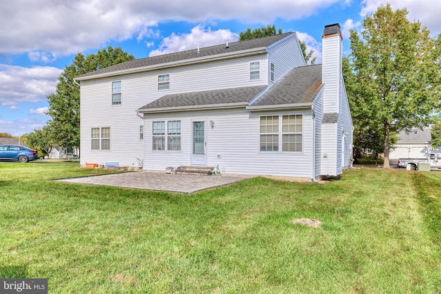 rear view of property featuring a lawn, a chimney, and a patio
