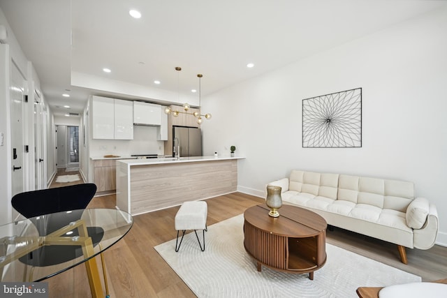 living room featuring light wood-type flooring, recessed lighting, and baseboards