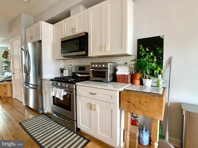 kitchen featuring appliances with stainless steel finishes, backsplash, white cabinets, and a toaster