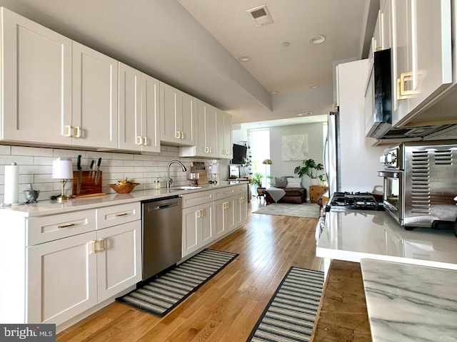kitchen featuring white cabinets, a sink, light countertops, stainless steel dishwasher, and visible vents