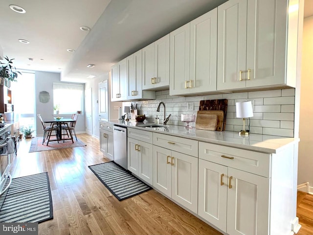 kitchen with baseboards, a sink, light wood finished floors, and dishwasher