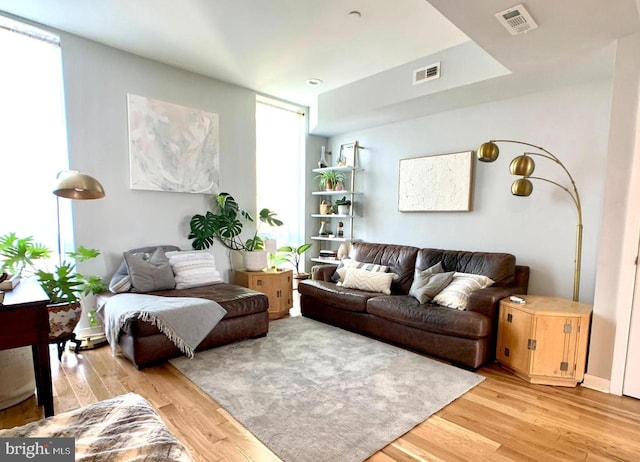 living room featuring visible vents, light wood-style flooring, and plenty of natural light