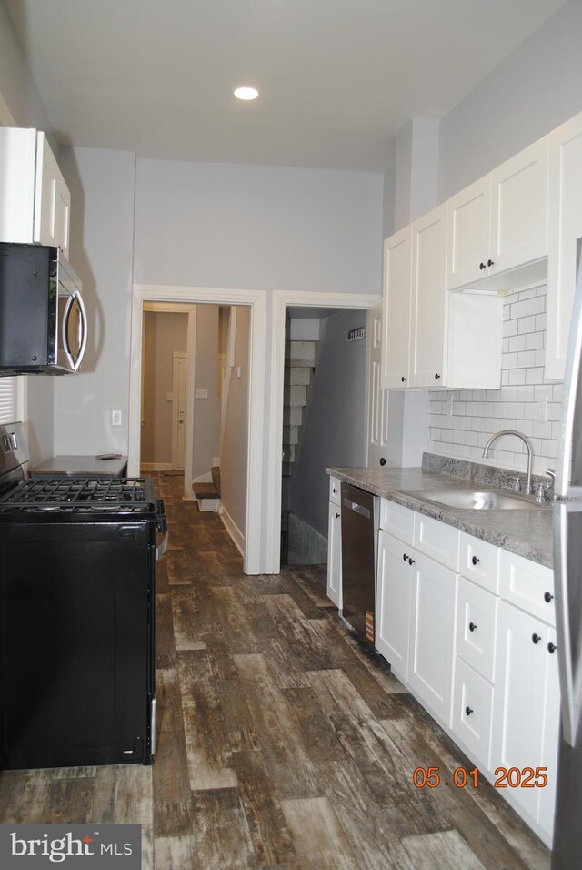 816 S Beaver St, York, PA 17403 - kitchen featuring appliances with stainless steel finishes, a sink, tasteful backsplash, dark wood-style flooring, and white cabinetry