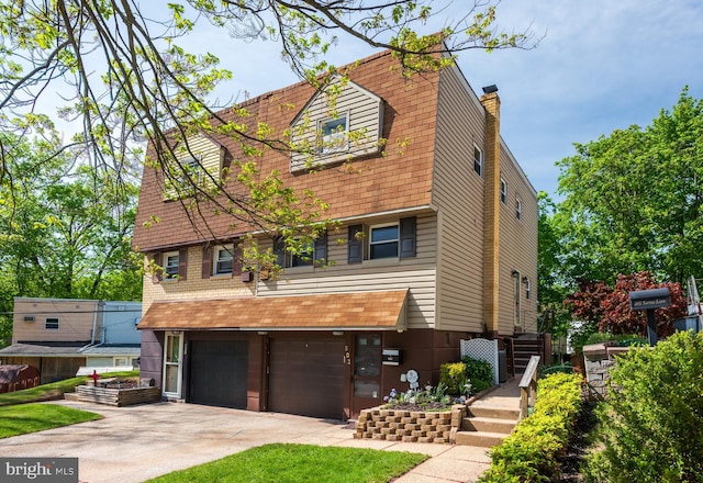 view of front of home featuring an attached garage, driveway, and a chimney