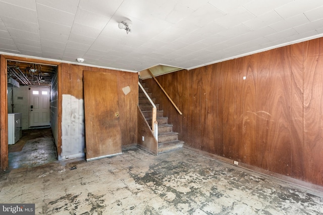 basement featuring stairway, wood walls, tile patterned floors, and washer / dryer