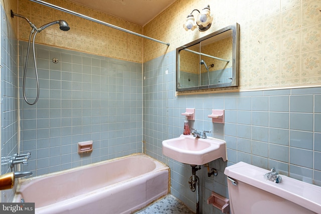 bathroom featuring shower / bathtub combination, toilet, tile walls, wallpapered walls, and a sink