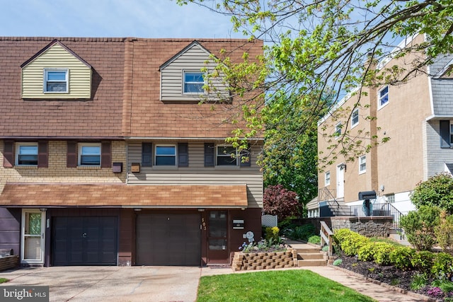 view of front of home featuring an attached garage, driveway, and a shingled roof
