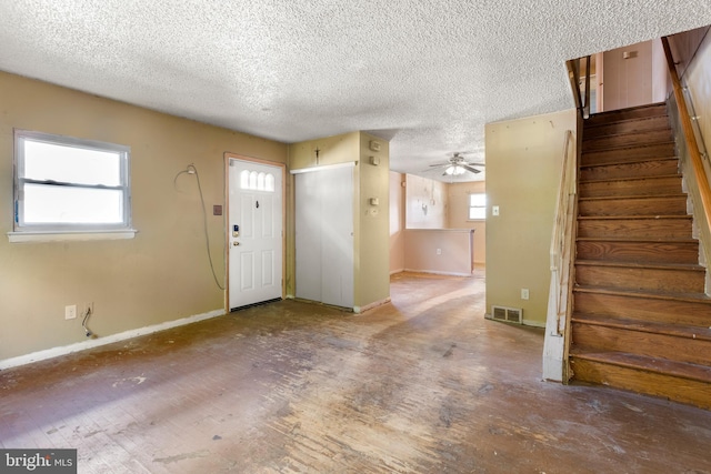 entryway with stairway, baseboards, a textured ceiling, and visible vents