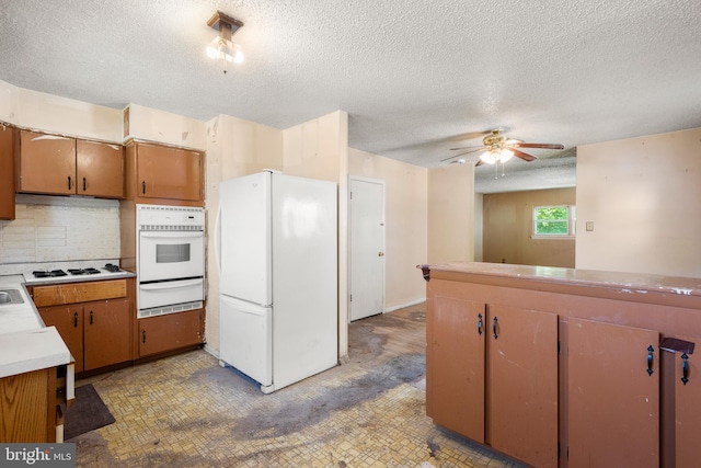 kitchen featuring white appliances, brown cabinets, a textured ceiling, and a warming drawer