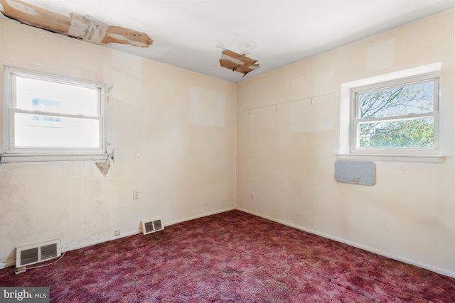carpeted empty room featuring baseboards and visible vents