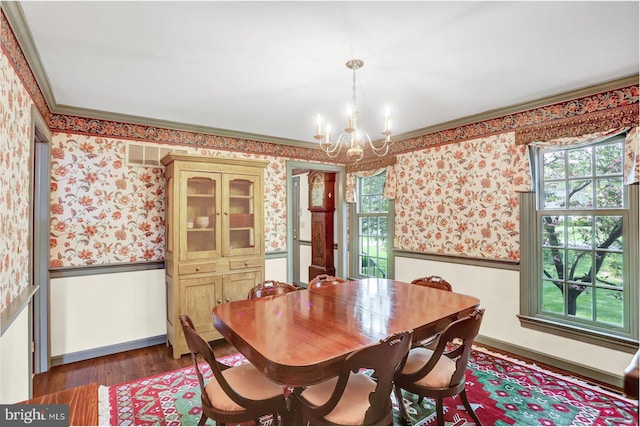 dining space with crown molding, wainscoting, a chandelier, wallpapered walls, and wood finished floors