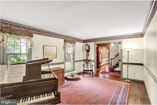 sitting room with crown molding, plenty of natural light, wood-type flooring, and stairs