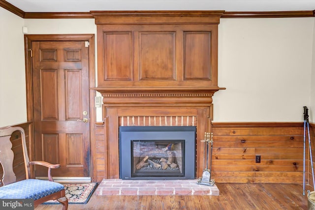 interior details featuring ornamental molding, a brick fireplace, and wood finished floors