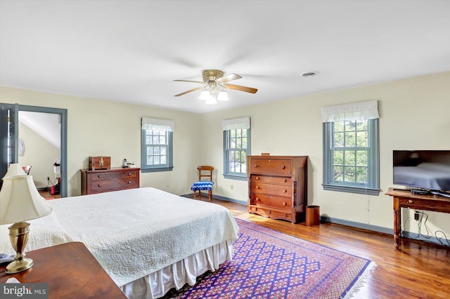 bedroom with baseboards, a ceiling fan, wood finished floors, and visible vents