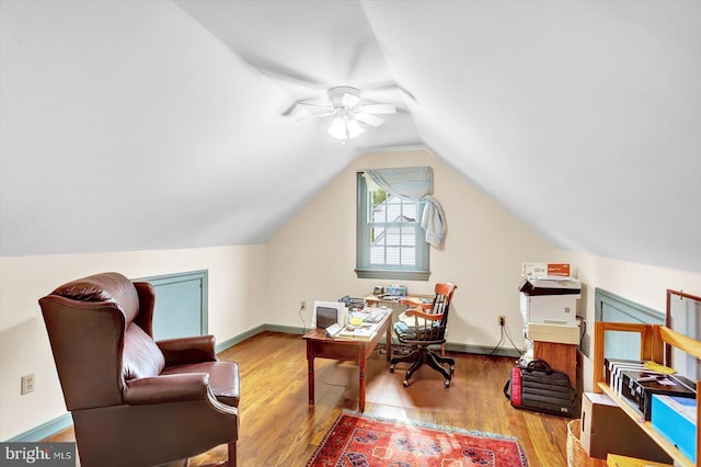 office space featuring a ceiling fan, baseboards, wood finished floors, and lofted ceiling