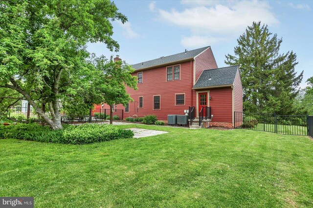 rear view of property featuring a lawn, fence, central air condition unit, and a chimney
